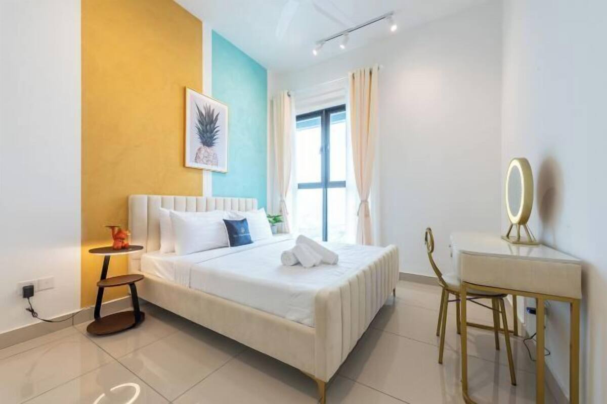 Un dormitorio con cama, mesita de noche, silla y ventana con cortinas.