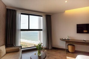 Une chambre d’hôtel avec une grande fenêtre, un canapé, un bureau et une télévision.