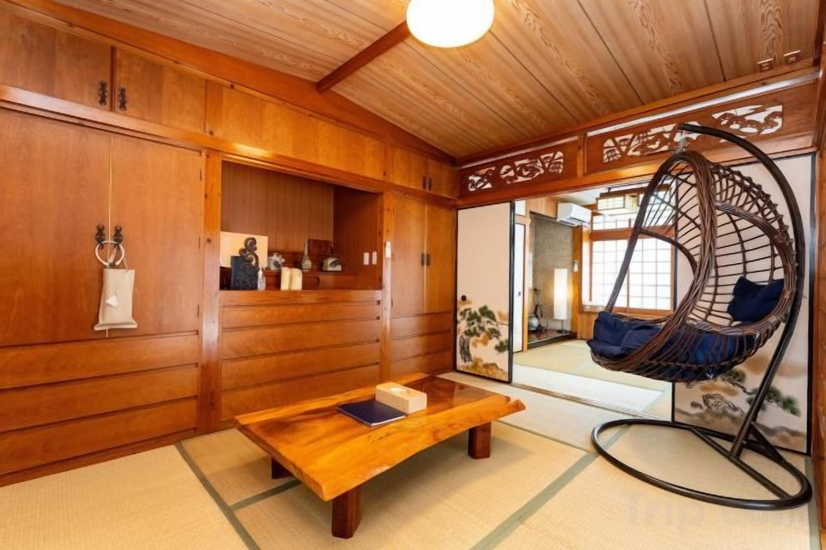 A traditional Japanese room with a wooden interior, a hanging chair, and a tatami mat floor.