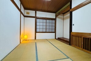 A traditional Japanese room with tatami flooring, a sliding door, and a window with a grid pattern.
