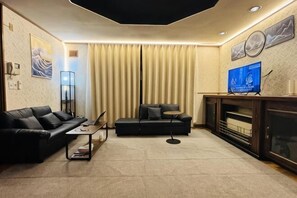 A living room with a sofa, a coffee table, a TV, and a fireplace.