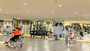 A gym with various exercise machines, mirrors, and a tiled floor. - Ai-Stay 78 at Shore 2 T1 (Pasay)