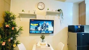 A small kitchen with a TV mounted on the wall, a clock, and a refrigerator. - Ai-Stay 78 at Shore 2 T1 (Pasay)