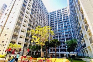 A high-rise building with multiple floors, surrounded by greenery and a playground. - Ai-Stay 78 at Shore 2 T1 (Pasay)