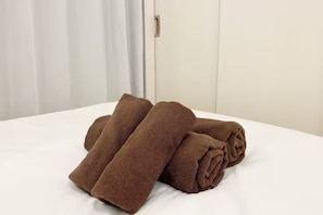 A bed with neatly folded brown towels. - SunStay Tachiaikawa II (Tokyo)