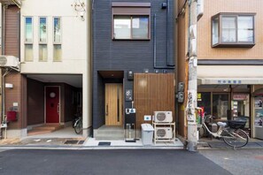 A building with a dark facade, a wooden door, and a small entrance with a bicycle parked outside. - EI･ETSU (Osaka)