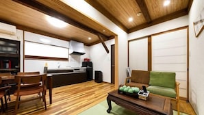 A compact living space with a wooden floor, a dining table with chairs, a sofa, and a coffee table. - AOU・KANZOU (Osaka)