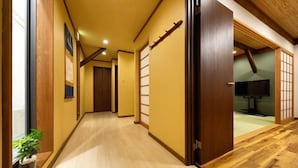 A hallway with wooden flooring, a sliding door, and a television in the adjacent room. - AOU・KANZOU (Osaka)