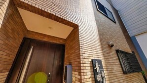 A building entrance with a wooden door, a mailbox, and a sign on the wall. - AOU・KANZOU (Osaka)