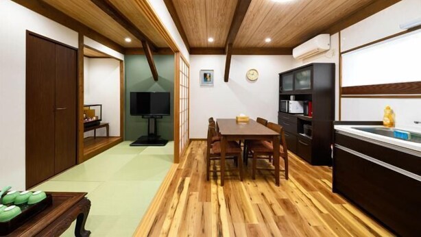 A compact kitchen with wooden flooring, a dining table, and a built-in oven. - AOU・KANZOU (Osaka)