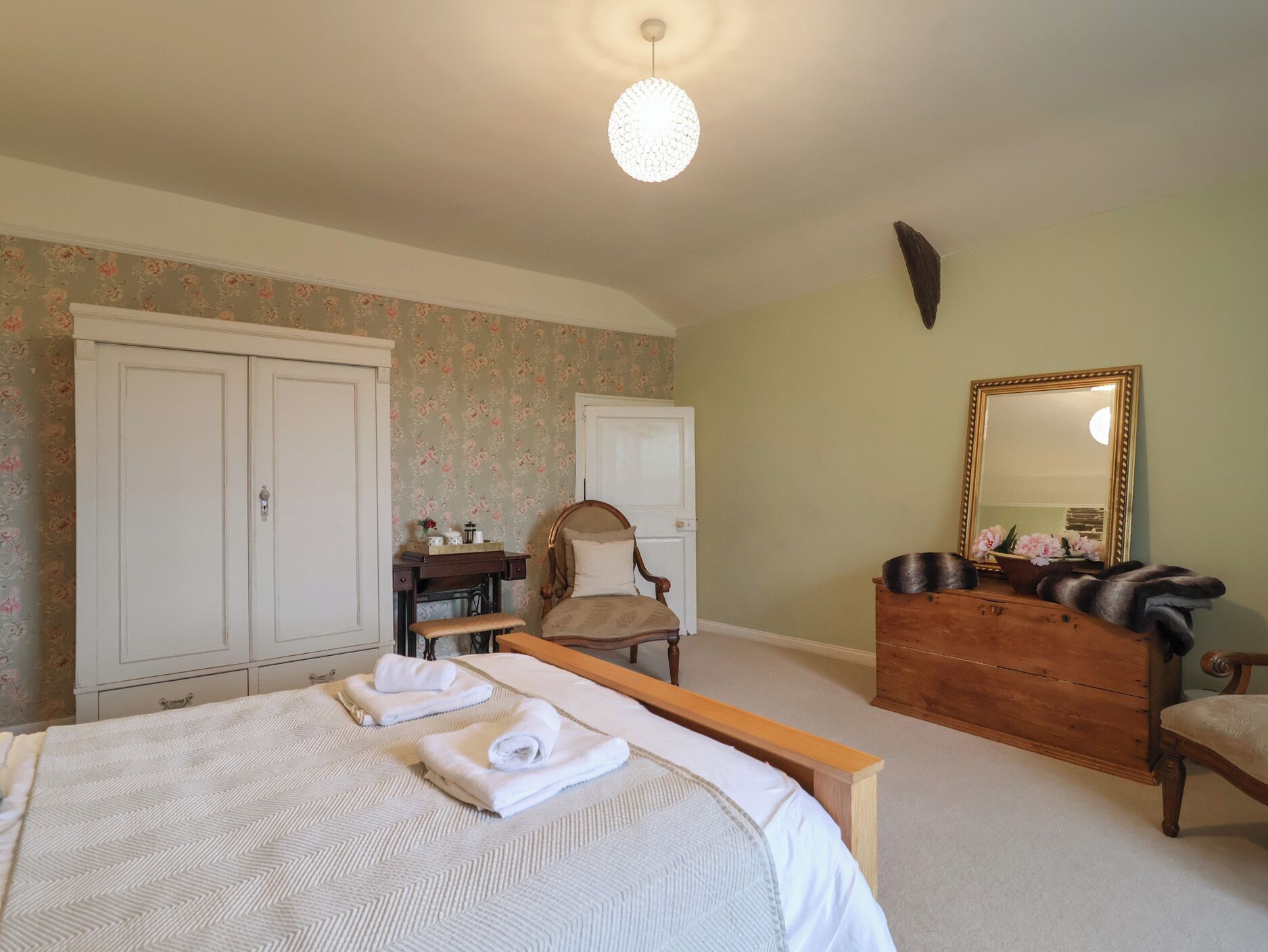 A bedroom with a bed, a dresser, a chair, a desk, and a wardrobe.