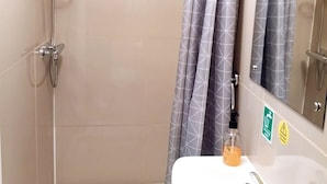 A bathroom with a shower, a sink, and a mirror. -  Ground-Floor Super King or Twin Studio Apartment with Free Private Parking (Portsmouth)