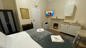 A hotel room with a bed, a desk, a television, a fireplace, and a kitchenette. -  Ground-Floor Super King or Twin Studio Apartment with Free Private Parking (Portsmouth)