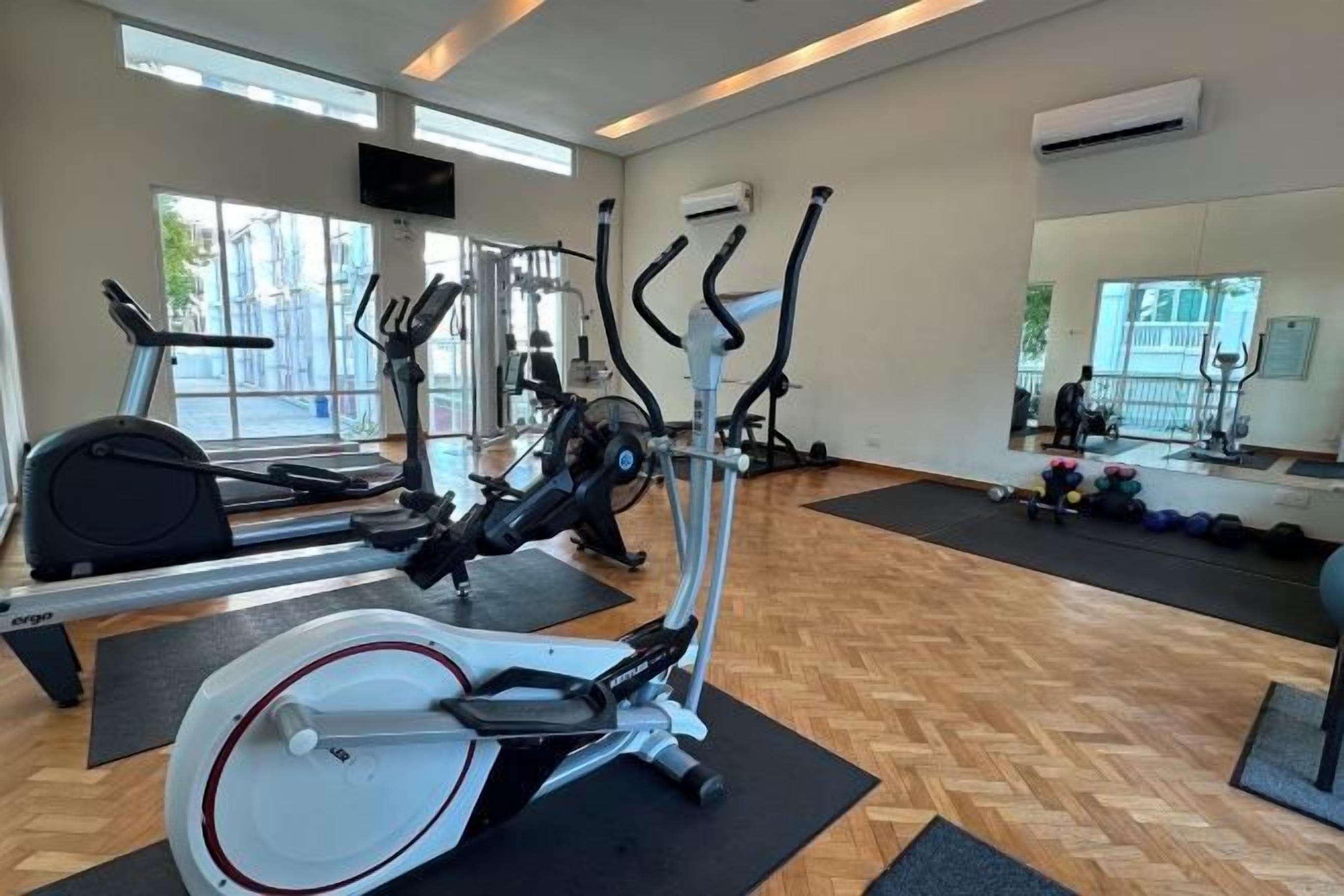 A gym with exercise equipment, a mirror, and a window.