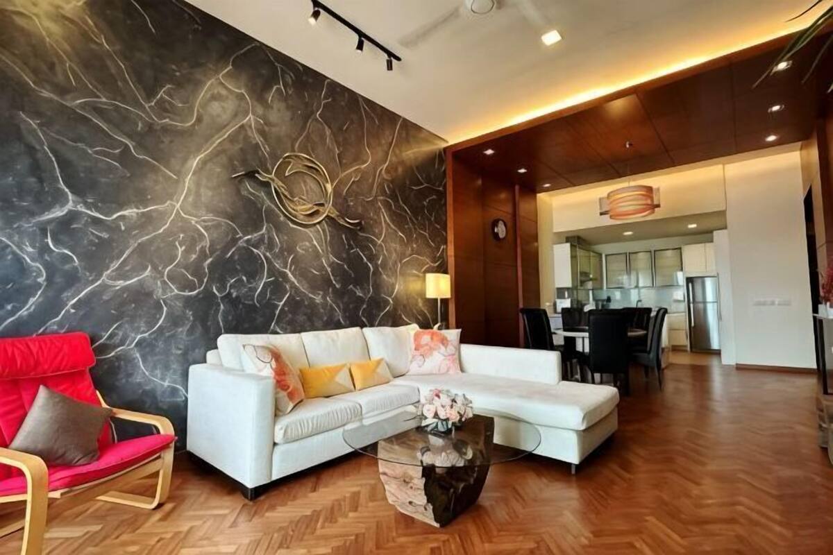 A modern living room with a marble wall, a white sofa, a red chair, and a wooden floor.