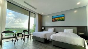 Een moderne hotelkamer met twee bedden, een balkon en uitzicht, en een schilderij aan de muur.