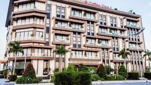 Een meerlaags hotel met balkons, palmbomen en een bord waarop staat 'DIAMOND GROFFEE View 6'.