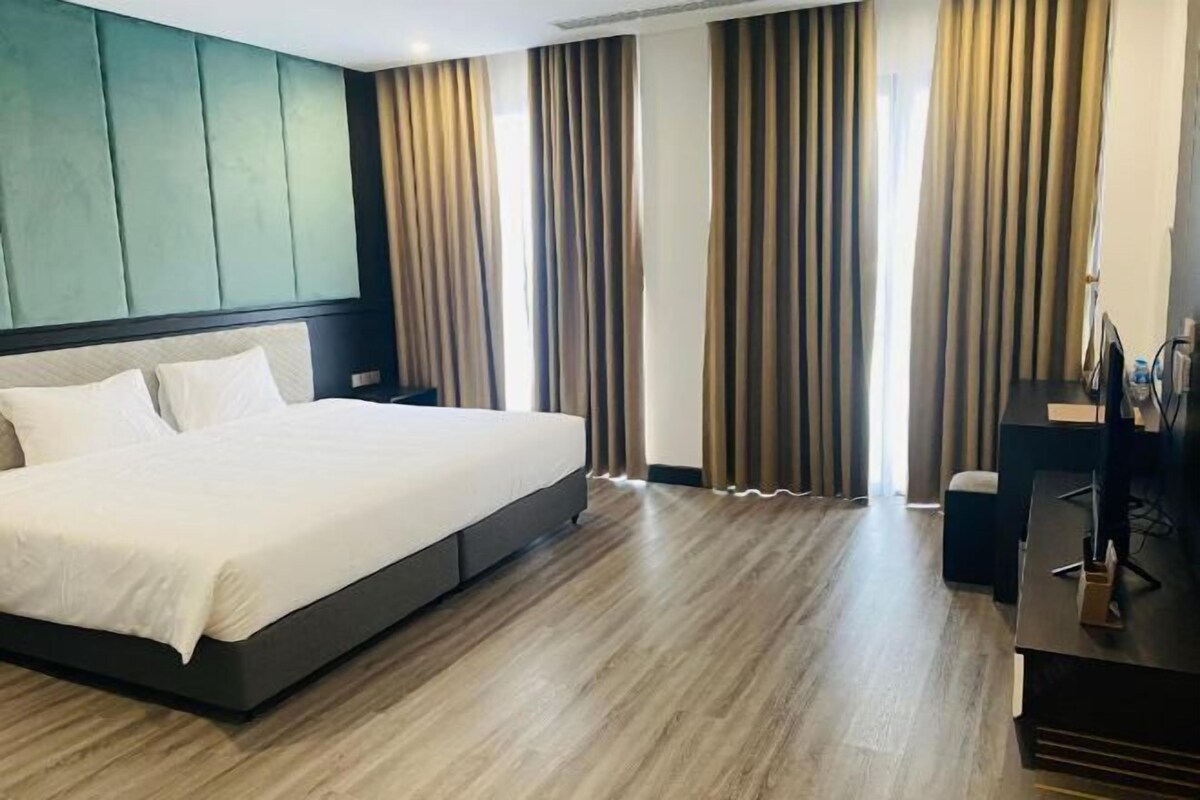 A modern hotel room with a large bed, a desk, and a computer.