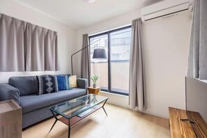 A modern living room with a sofa, glass coffee table, and a view of the outside. - Higashi Mukoujima 6 chome (Tokyo)