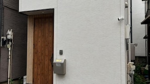 A building entrance with a wooden door, a mailbox, and a security camera. - Higashi Mukoujima 6 chome (Tokyo)