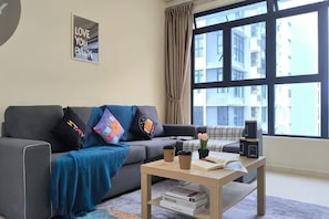 Ein Wohnzimmer mit einer Couch, einem Couchtisch und einem Fenster mit Vorhängen.