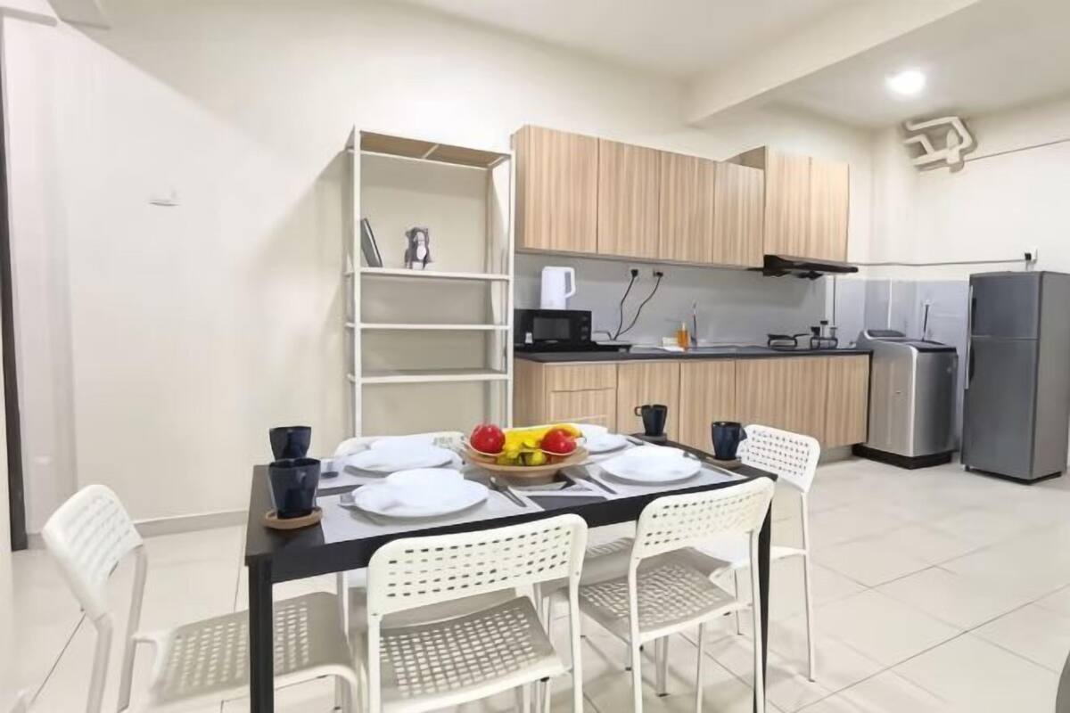 Une cuisine moderne avec des meubles blancs, une table à manger dressée avec des assiettes et un panier de fruits.