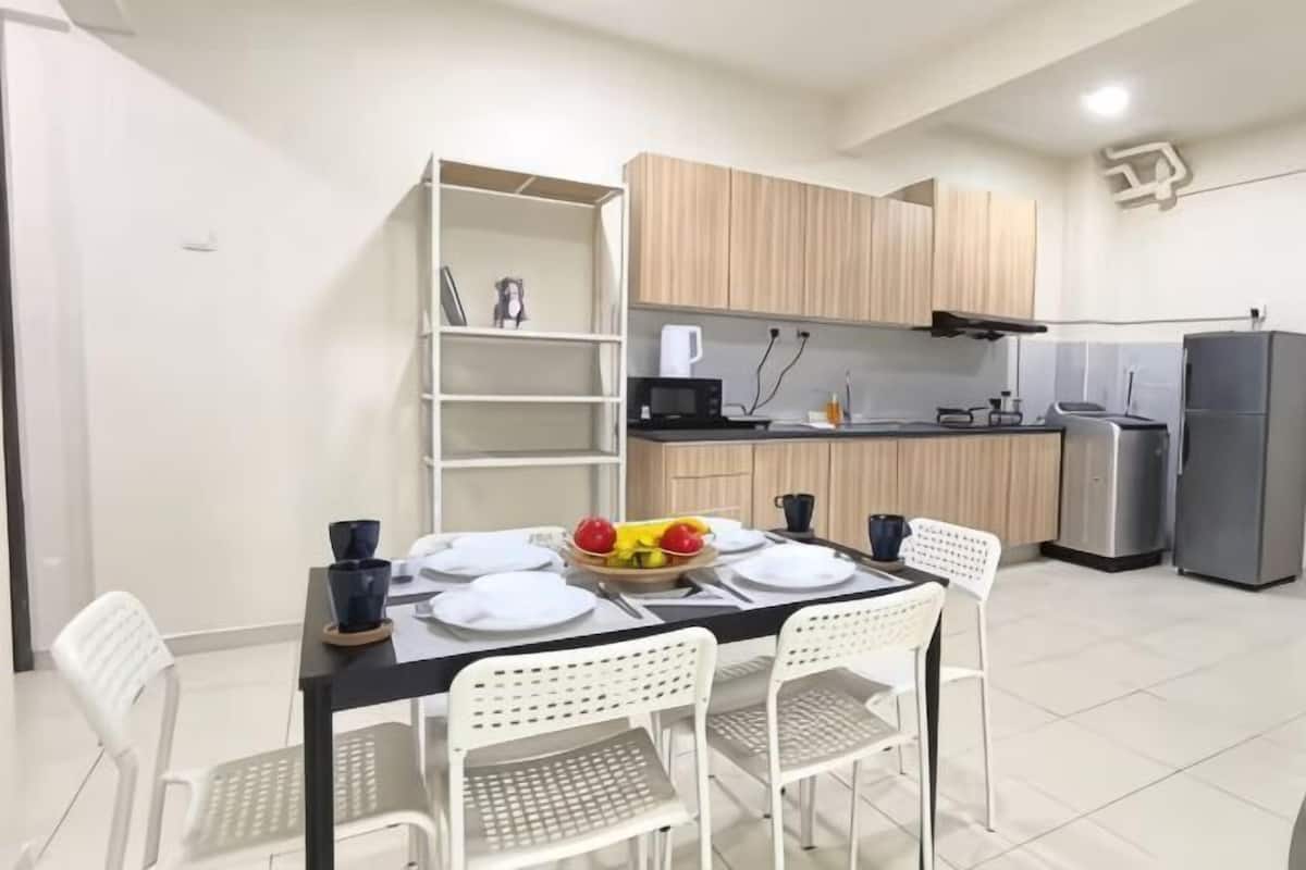 A modern kitchen with white cabinetry, a dining table set with plates, and a fruit bowl.