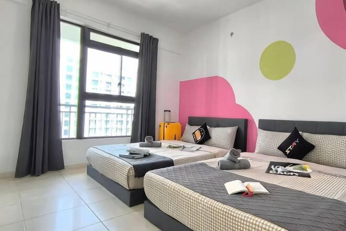 Une chambre d’hôtel avec deux lits, une fenêtre avec des rideaux, une valise et un mur orné de motifs abstraits.