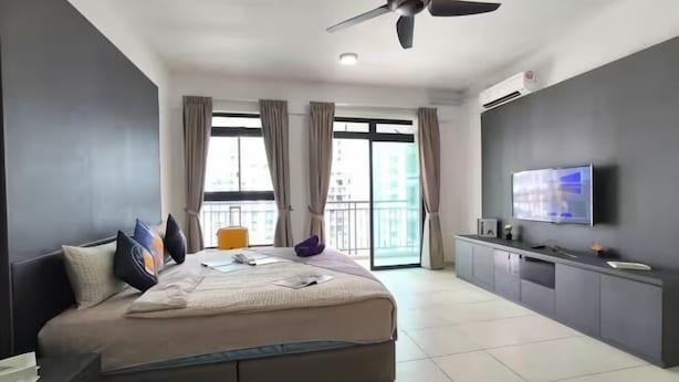 A modern hotel room with a large bed, a TV, a ceiling fan, and a balcony with curtains. - The Garden Homestay BySTAY (Sekudai)