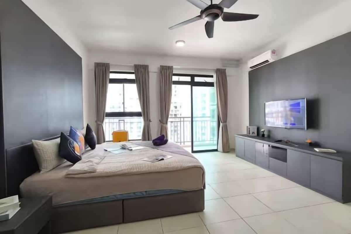 Ein modernes Hotelzimmer mit einem großen Bett, einem Fernseher, einem Deckenventilator und einem Balkon mit Vorhängen.