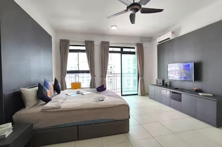 A modern hotel room with a large bed, a TV, a ceiling fan, and a balcony with curtains.. The Garden Homestay BySTAY