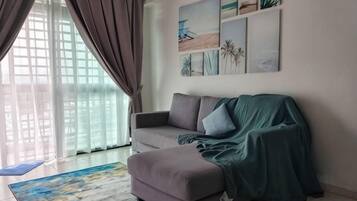 Ein Wohnzimmer mit Sofa, einer überdachten Fläche, einem Fenster mit Vorhängen und Wandbildern.