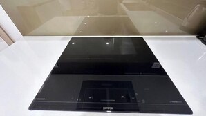 A black induction cooktop with a control panel on a white countertop. - 2BRS@Vinhomes Smart City (Hanoi)