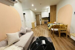 A living room with a sofa, a dining table with chairs, and a kitchen area in the background. - 2BRS@Vinhomes Smart City (Hanoi)