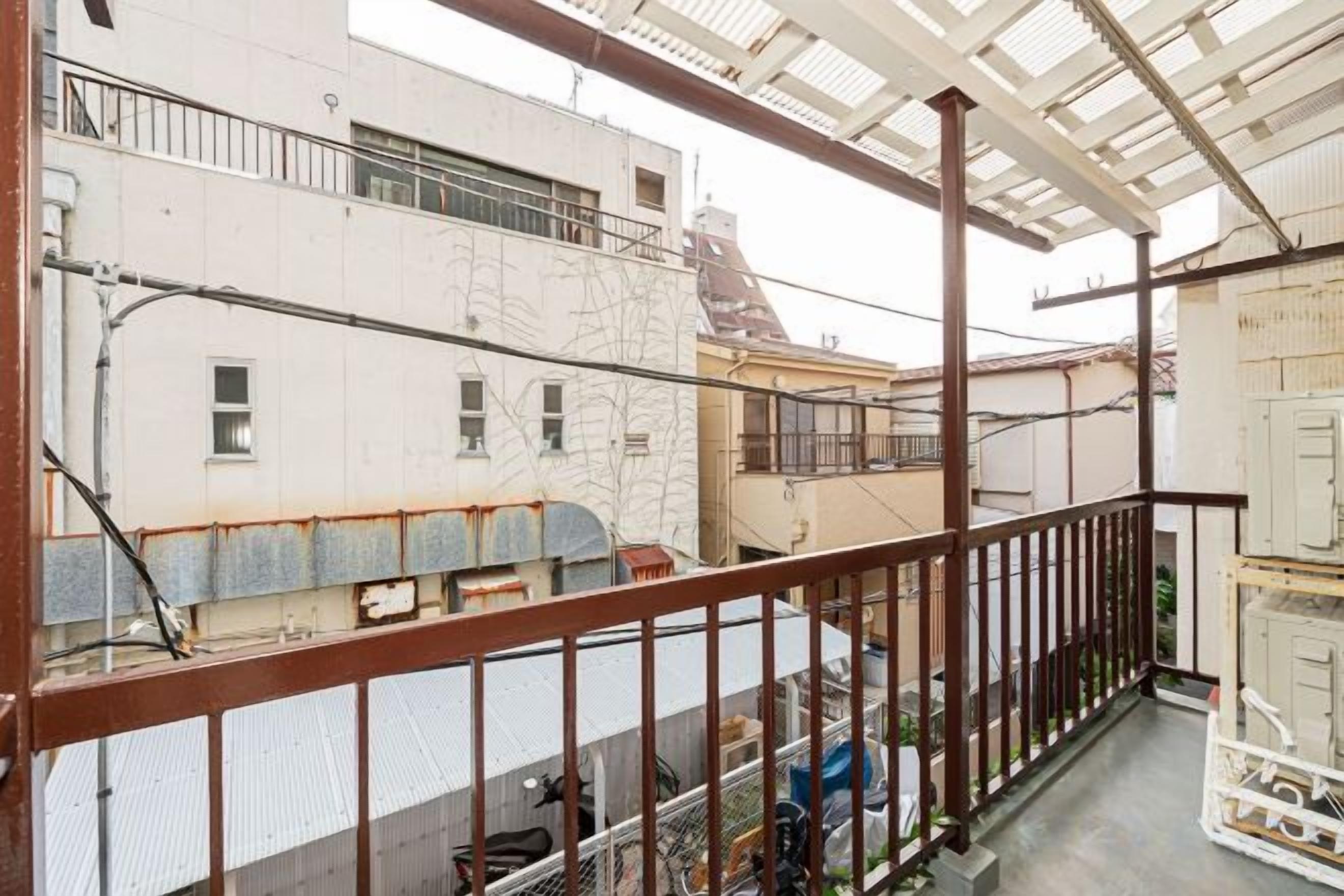 Un balcone con ringhiera metallica che si affaccia su un cortile con edifici.