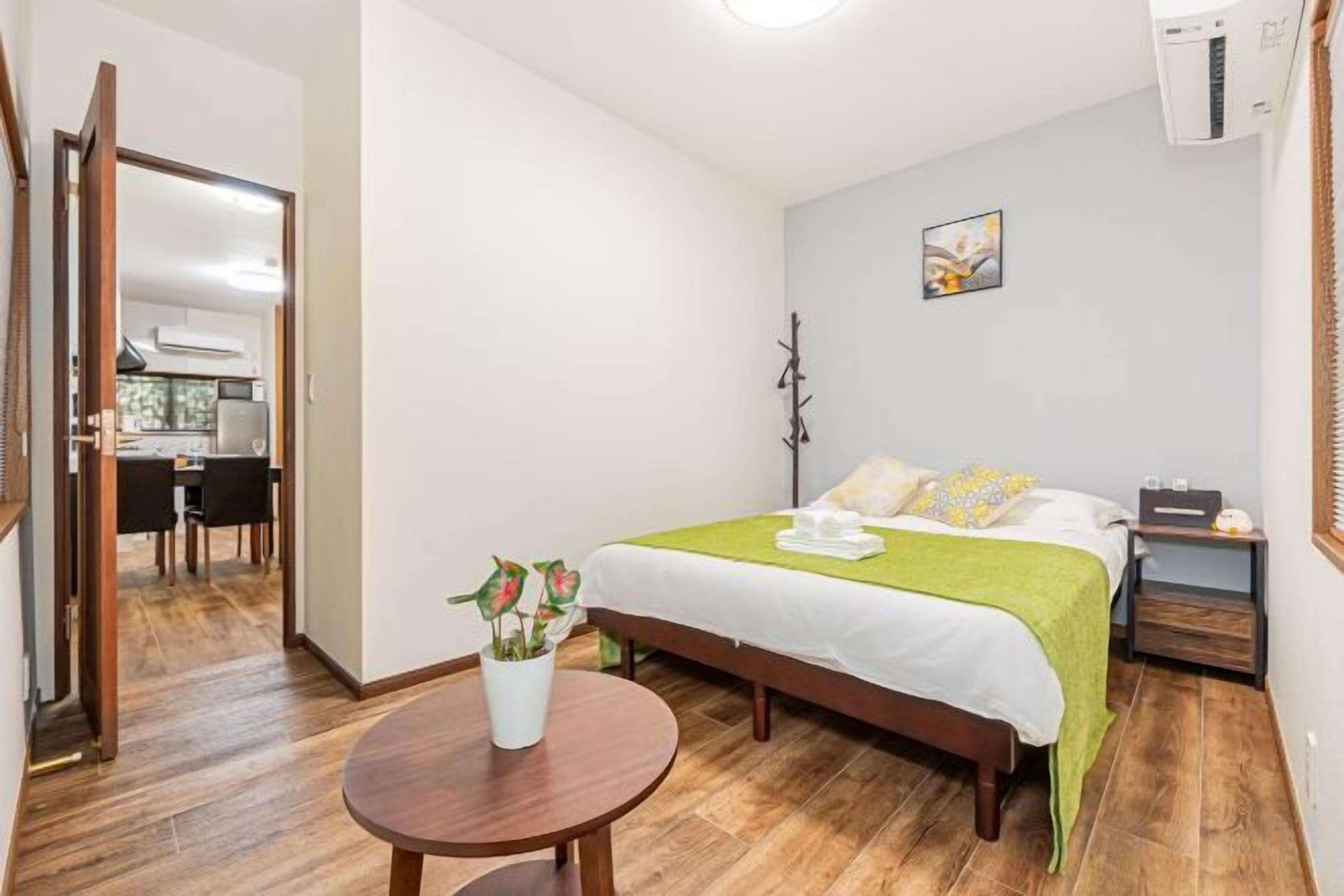 Ein Hotelzimmer mit einem Bett, einem runden Holztisch und einem kleinen Blumentopf.