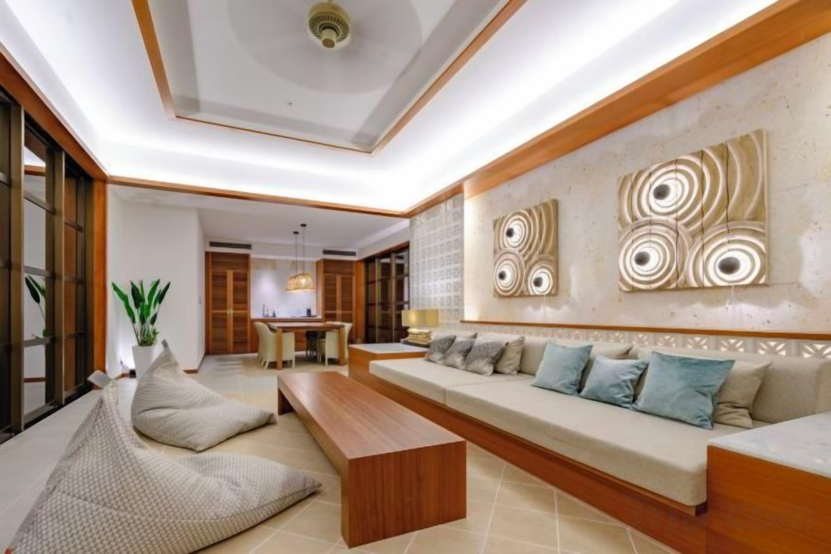 A modern living room with a sofa, a coffee table, and a dining area in the background.