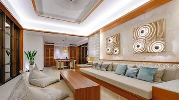 A modern living room with a sofa, a coffee table, and a dining area in the background.