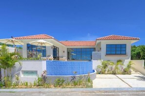 A modern house with a swimming pool, large windows, and a tiled roof. - Ciel et mer SESOKO Suite (Motobu)