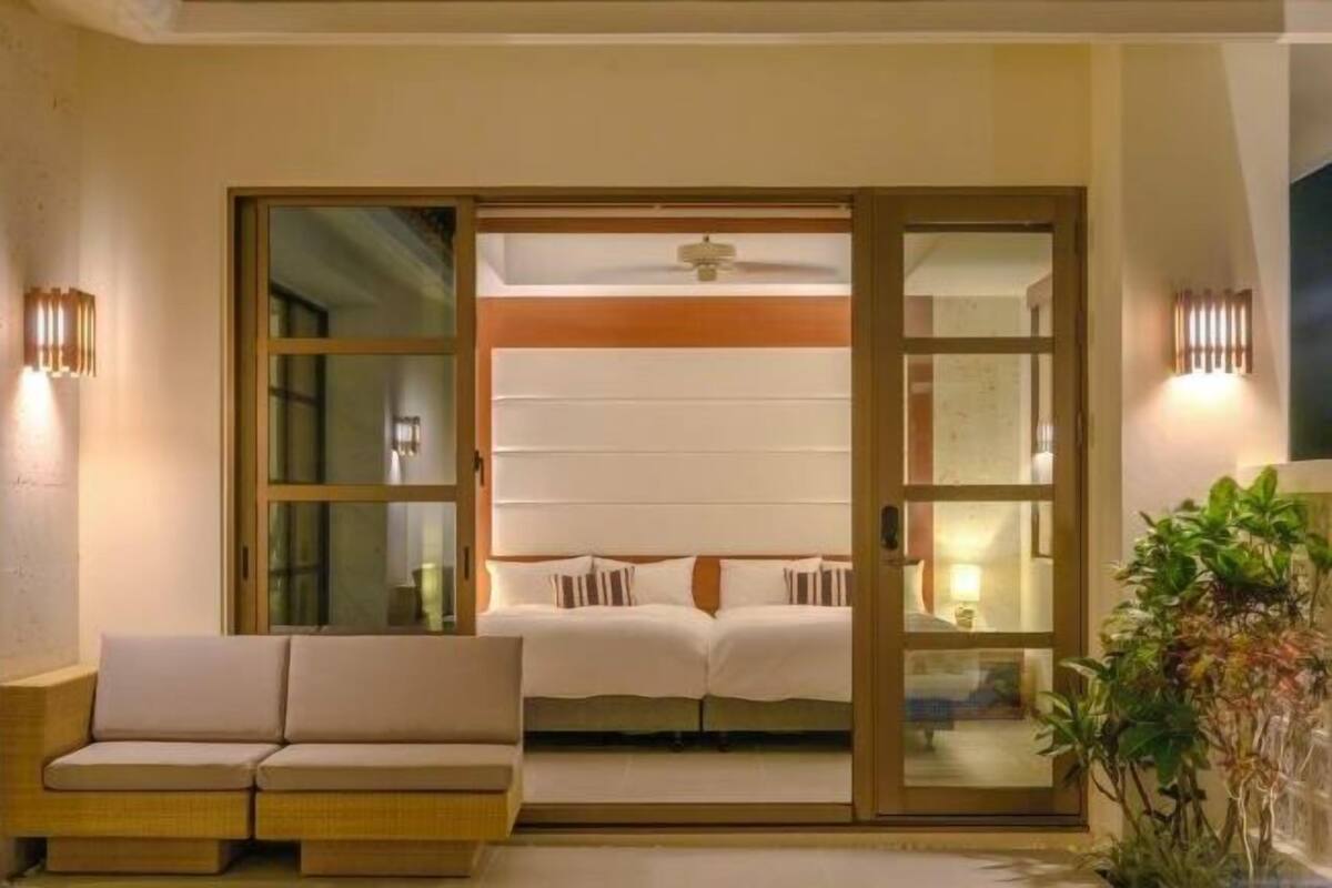 A room with a bed, a sofa, and a sliding door.