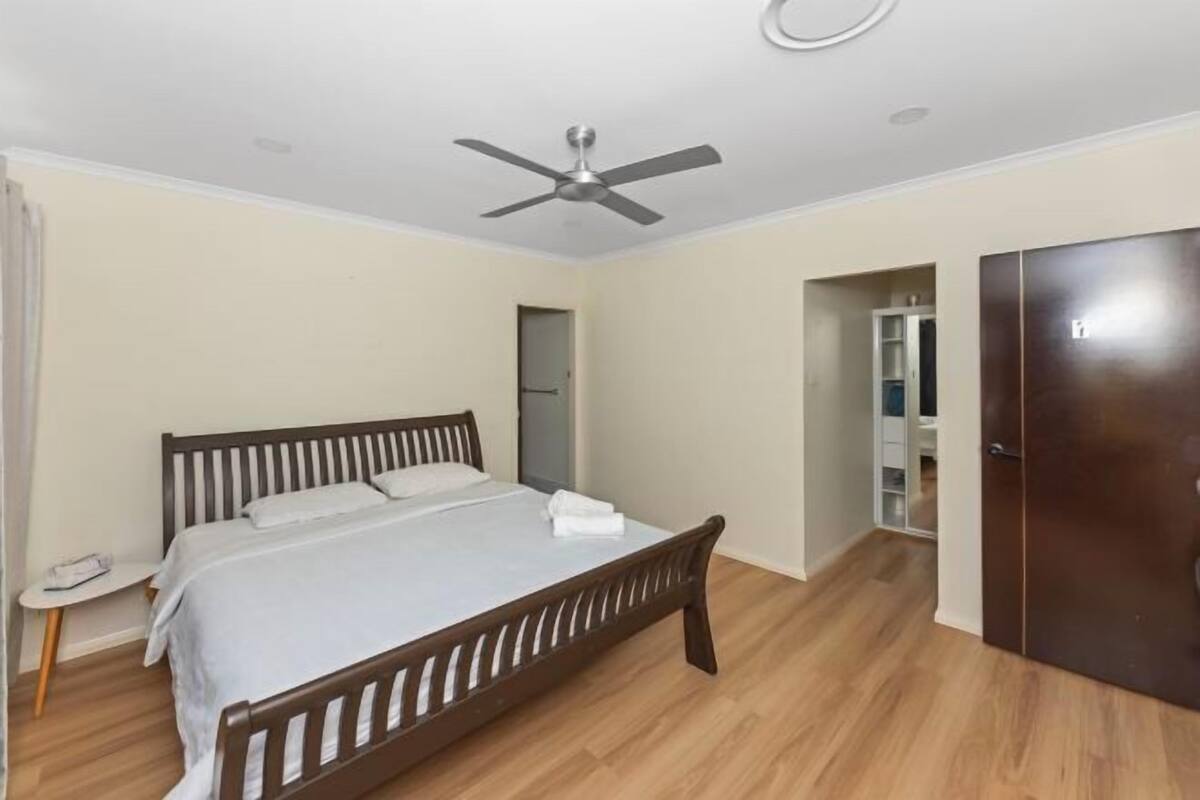 Une chambre à coucher comprenant un lit, un ventilateur de plafond, une armoire et une petite table de chevet.