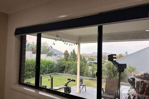 A room with a large window overlooking a garden, a ceiling fan, and a chair. - Holiday Place (North Rothbury)