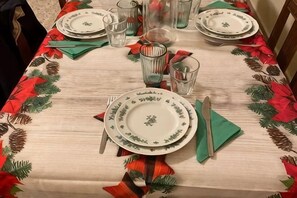 Een eettafel gedekt met borden, glazen en bestek, versierd met een feestelijk tafelkleed.