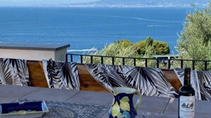 A terrace with a table, a bottle, and a view of the sea and a mountain. - Villa L'Ulivina - Indipendent Villa Garden & View (Sorrento)