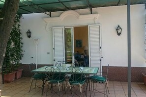 An outdoor patio with a table and chairs, a potted plant, and a door leading to an interior space. - Villa L'Ulivina - Indipendent Villa Garden & View (Sorrento)