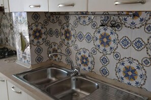 A kitchen with two stainless steel sinks, white cabinets, and patterned tile backsplash. - Villa L'Ulivina - Indipendent Villa Garden & View (Sorrento)