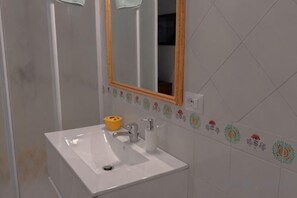 A bathroom with a white sink, a mirror, and a decorative tile border. - Villa L'Ulivina - Indipendent Villa Garden & View (Sorrento)