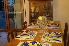 Une table à manger dressée avec des assiettes, des verres et un vase contenant une fleur jaune.