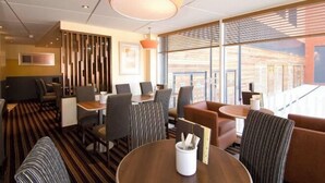 A modern hotel lobby with a striped carpet, wooden furniture, and large windows offering a view of the building's exterior. - Coventry City Centre (Coventry)