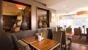 A restaurant with wooden tables and chairs, large mirrors, and decorative vases. - Coventry City Centre (Coventry)